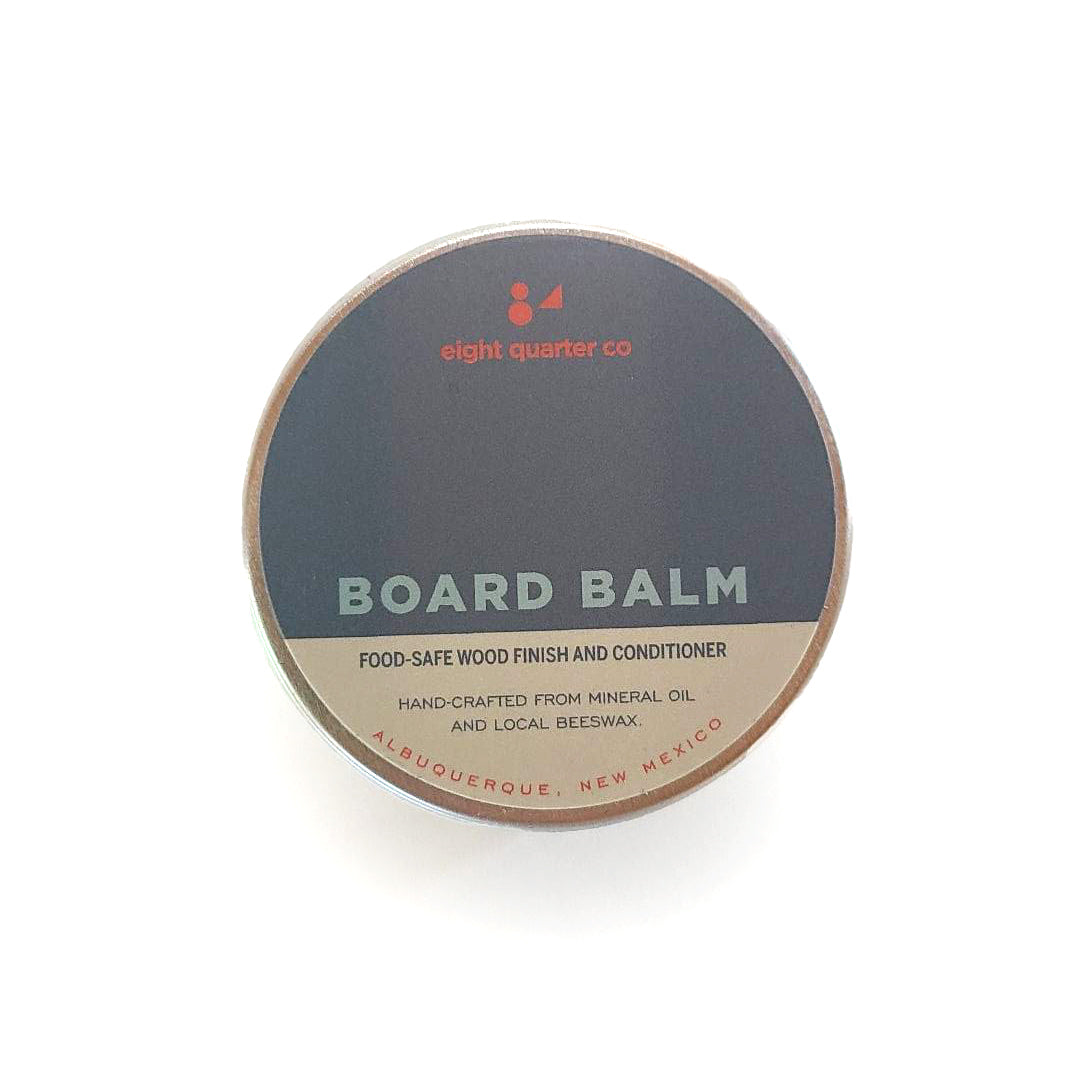 Overhead view of Board Balm tin on a white surface.